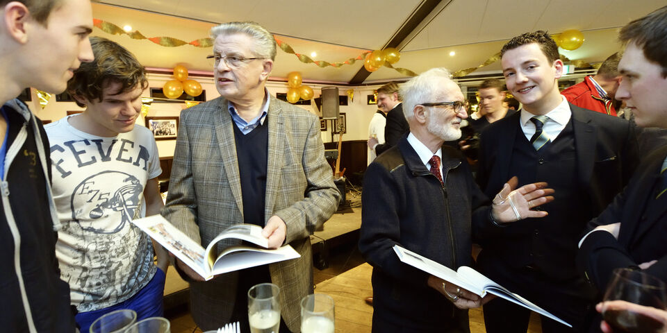 Jos Bedet (L) en Sjir Nijssen bladeren door het lustrumboek. Foto | Bart van Overbeeke